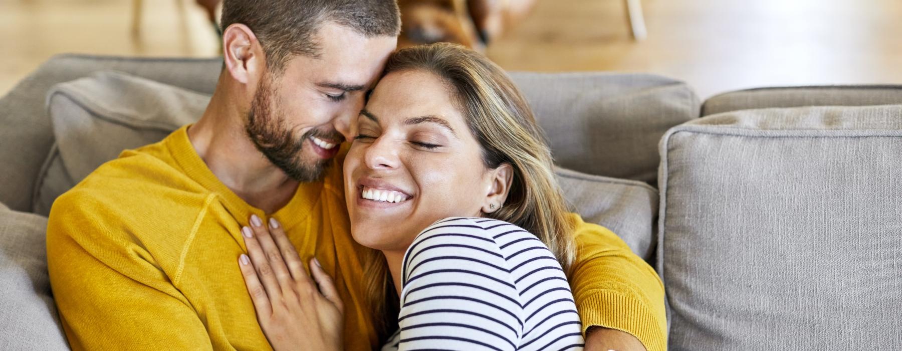 a man and woman sitting on a couch and smiling